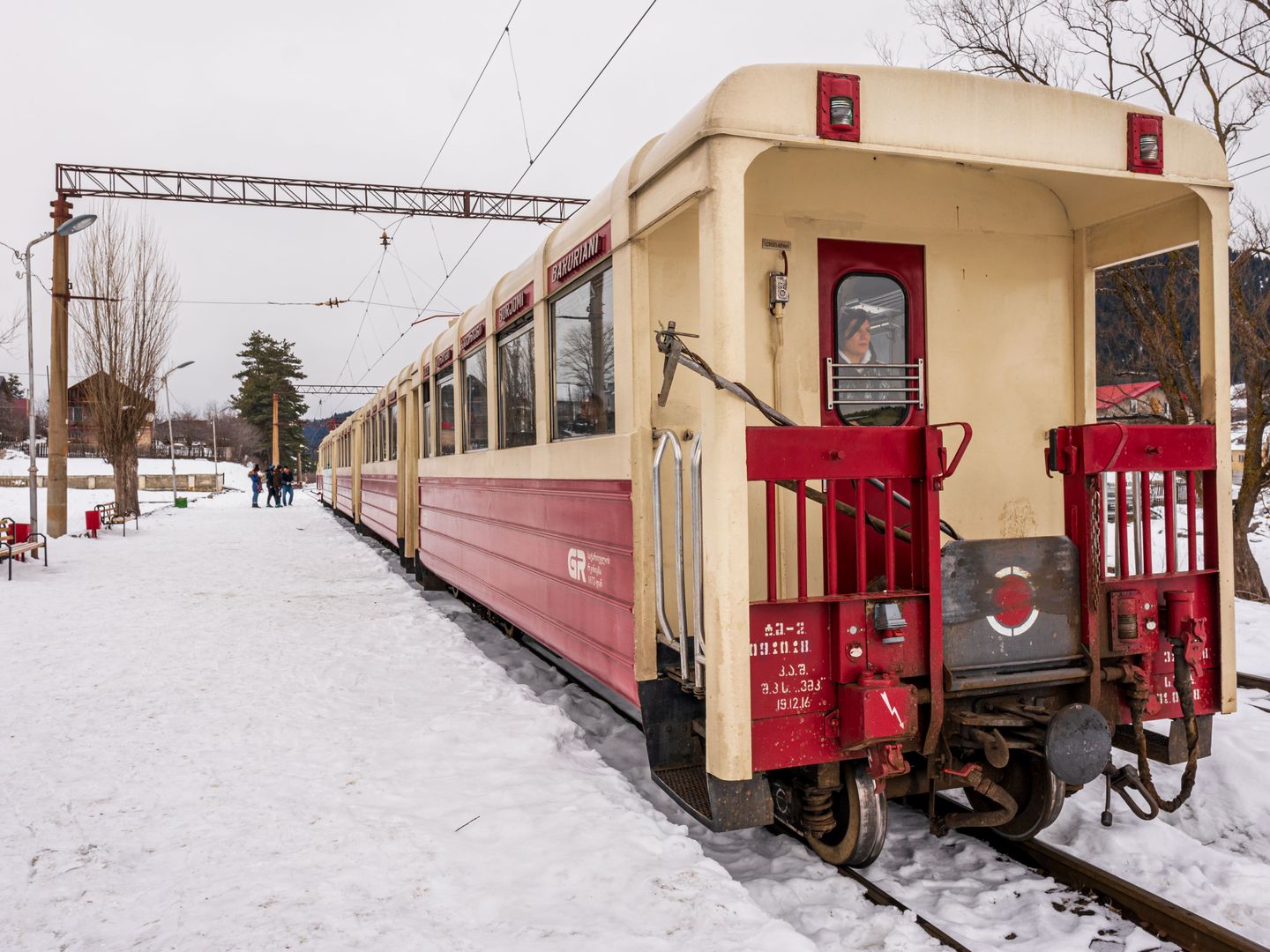 A vintage train waits at a snowy station in Georgia, showcasing transportation in winter.